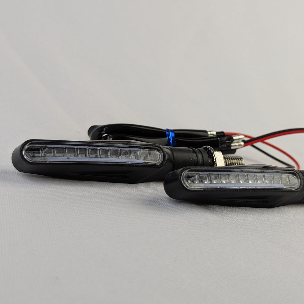 Two motorcycle turn signals with wiring on a gray background