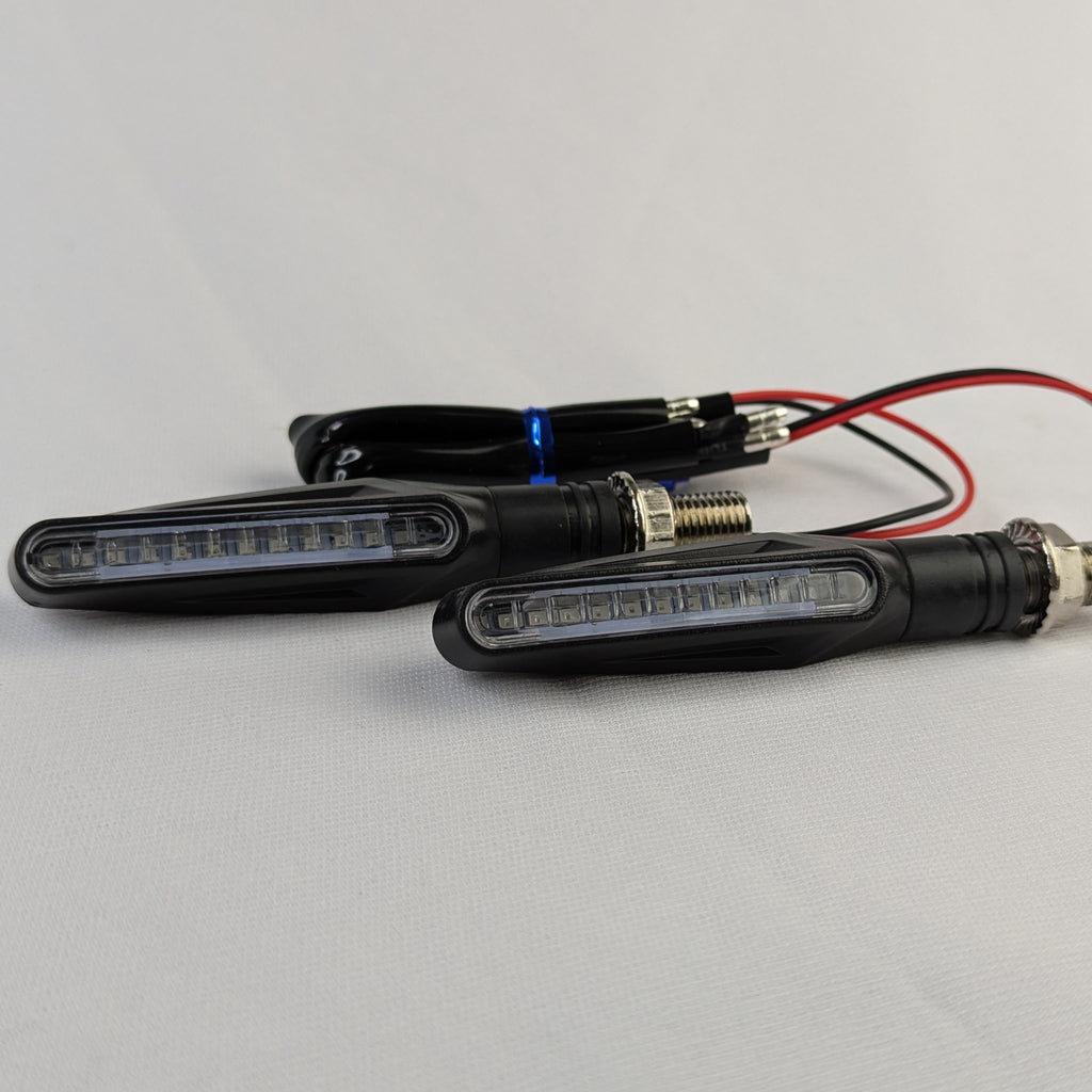 Two motorcycle turn signals with wiring on a gray background