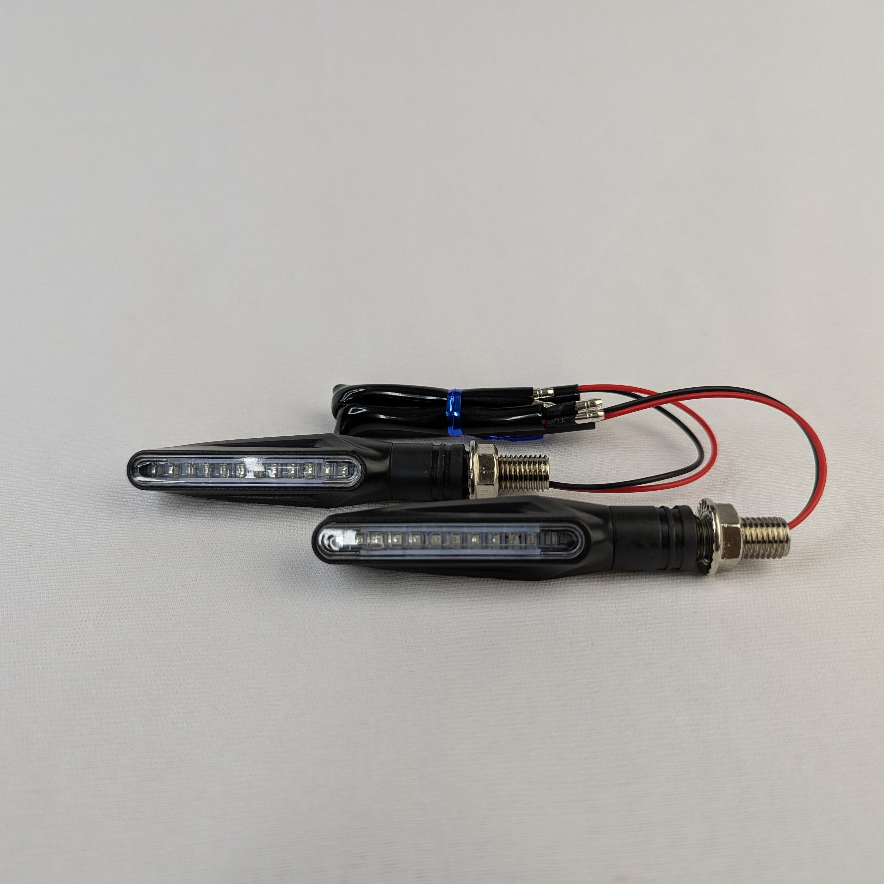 Two motorcycle turn signals with wiring on a gray background