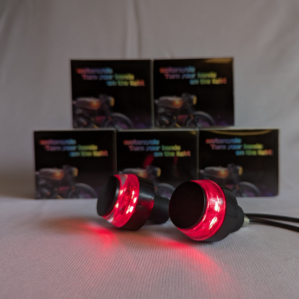 Red LED lights with black casings on a white background, with motorcycle-themed boxes in the background.