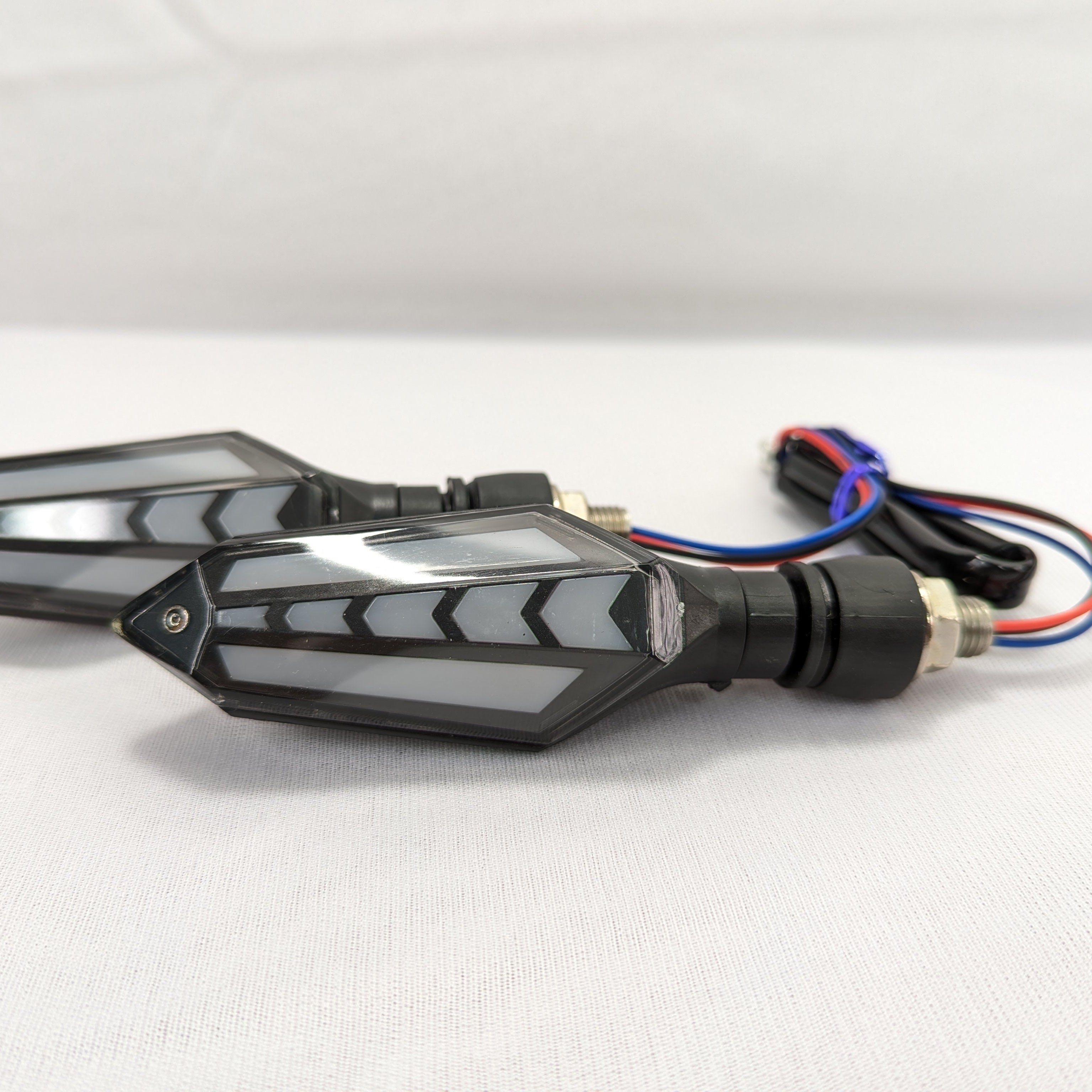 Pair of motorcycle turn signals with wiring on a white background