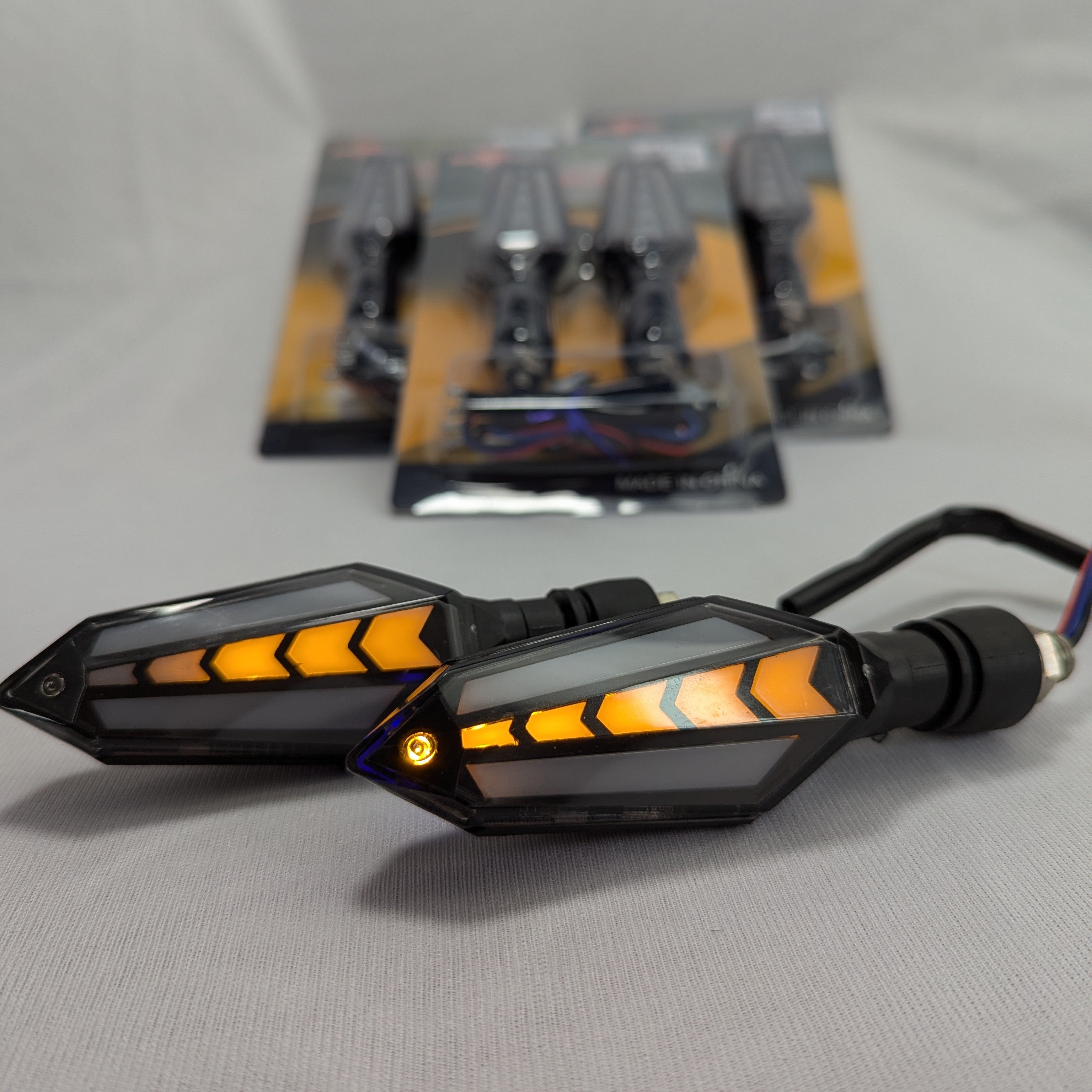 Motorcycle turn signals with orange indicators on a gray surface
