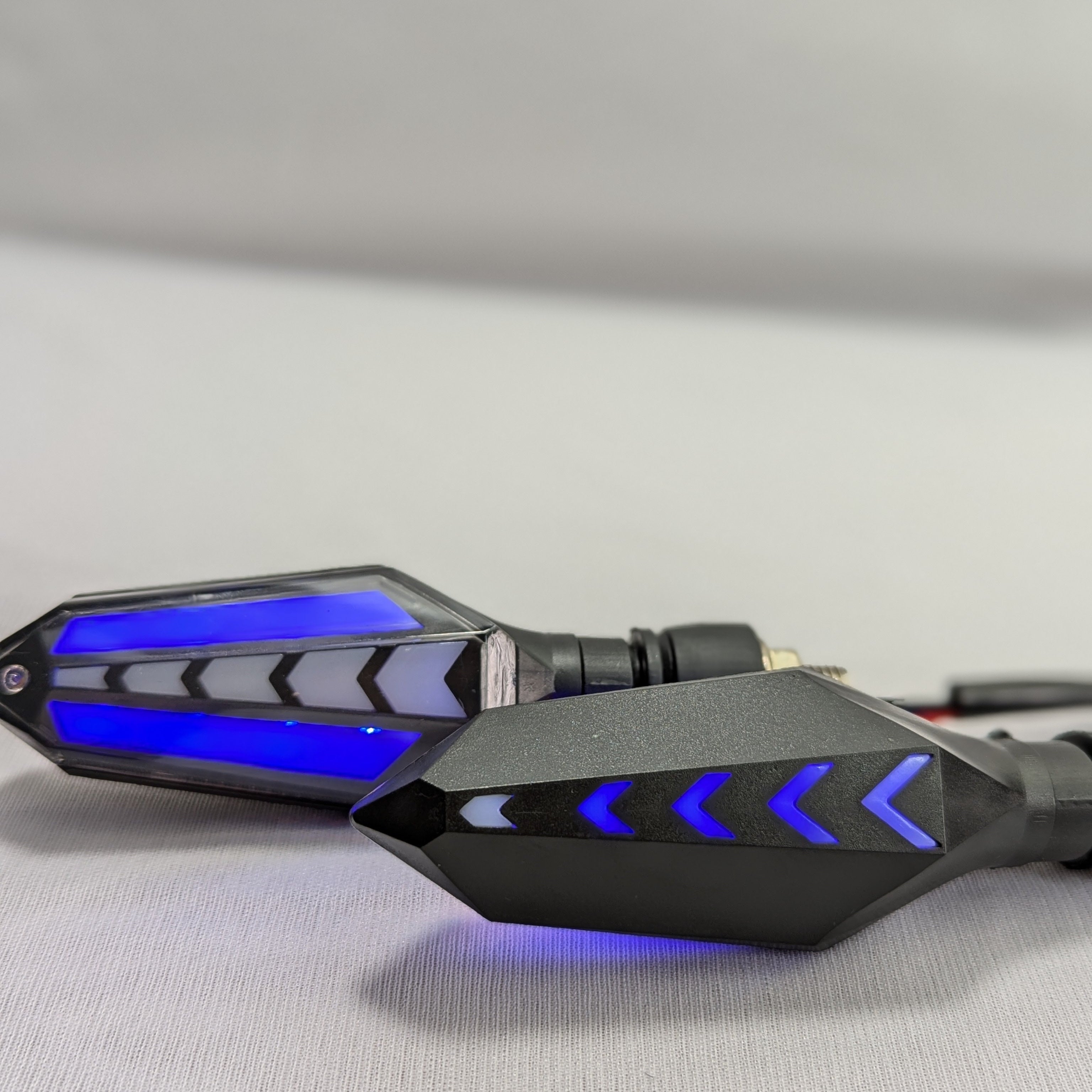 Black motorcycle mirrors with blue LED lights on a gray background