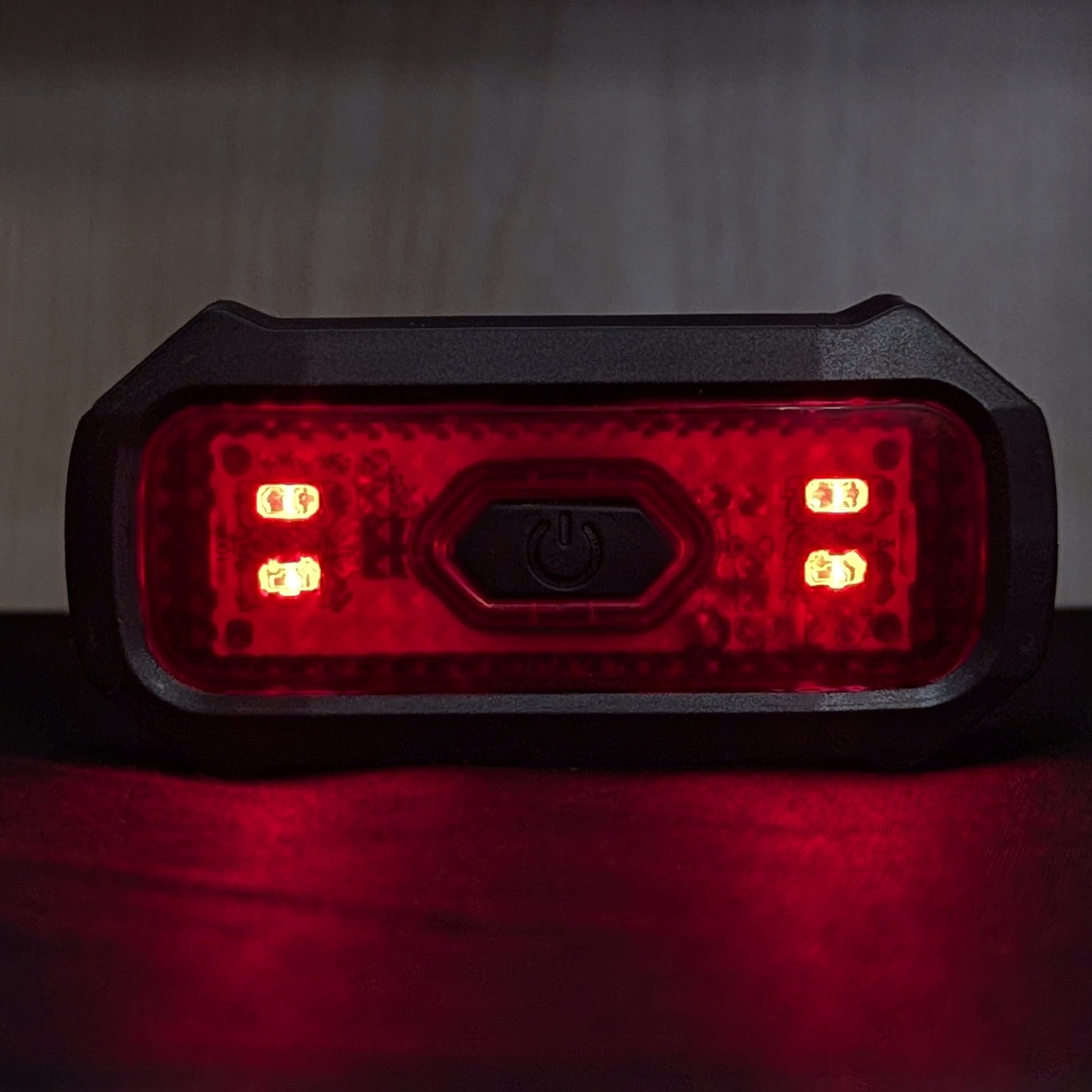 Red LED light with black casing on a dark background