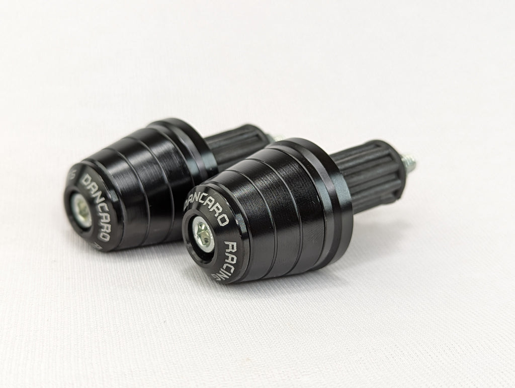 Two black motorcycle foot pegs with 'Dainese' branding on a white background