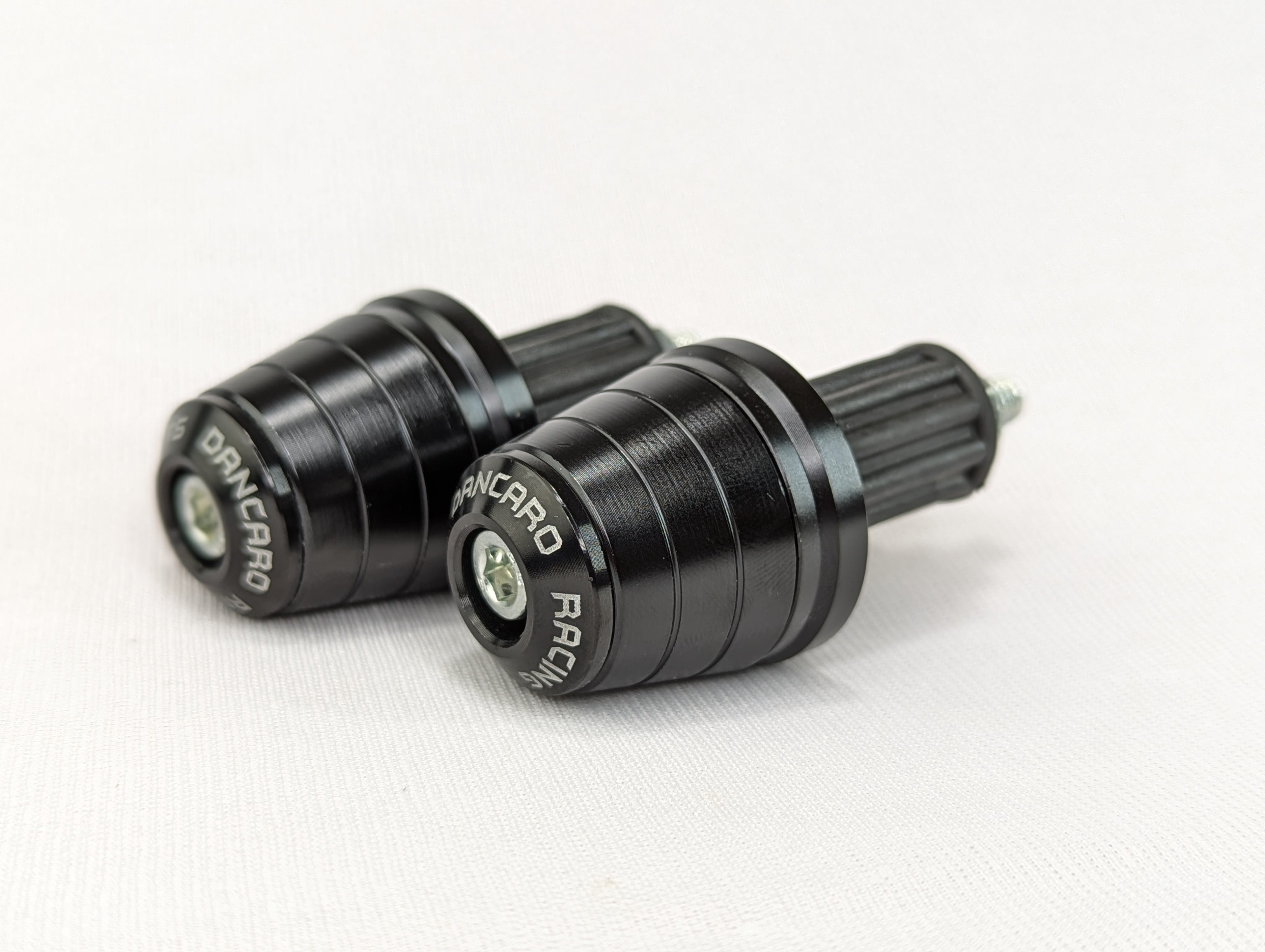 Two black motorcycle foot pegs with 'Dainese' branding on a white background