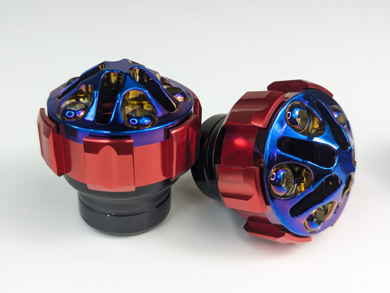 Two metallic knobs with red and blue finishes on a white background